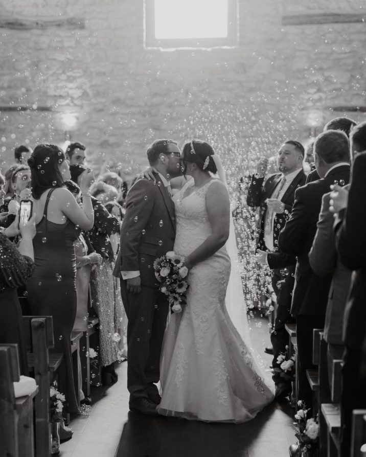 Bride and groom kissing in renovated barn during ceremony
