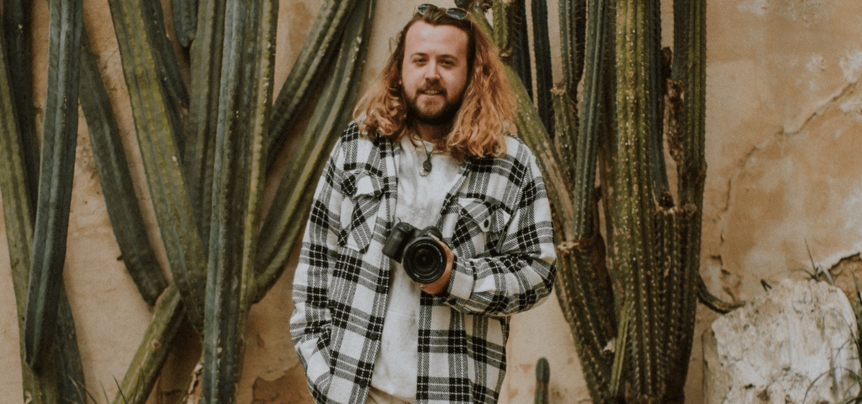 Male photographer outside stood in front of plants