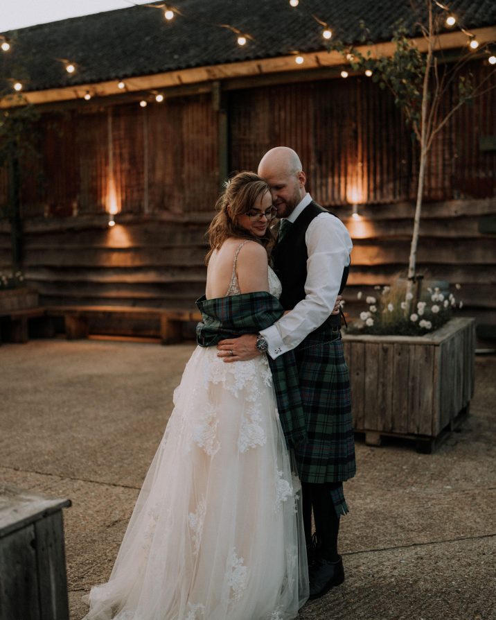 Bride and groom stood hugging outside at a barn wedding venue