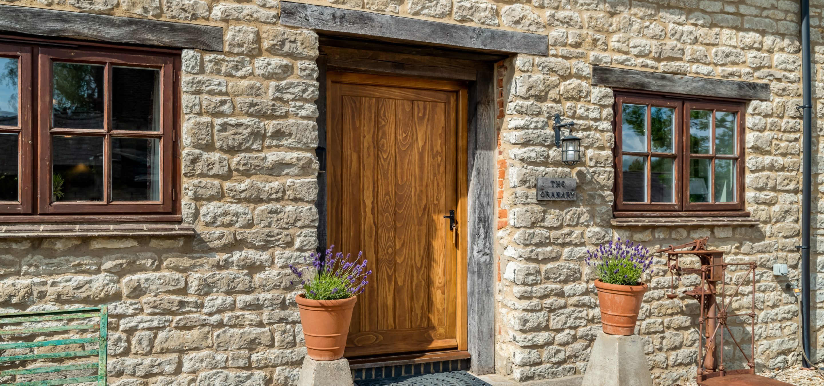 Front view of cottage with brown oak door and two plant pots