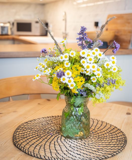 Flowers in a vase sat on wooden table in cottage kitchen